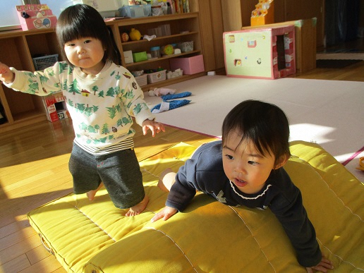 0歳児がマット山を登っている
